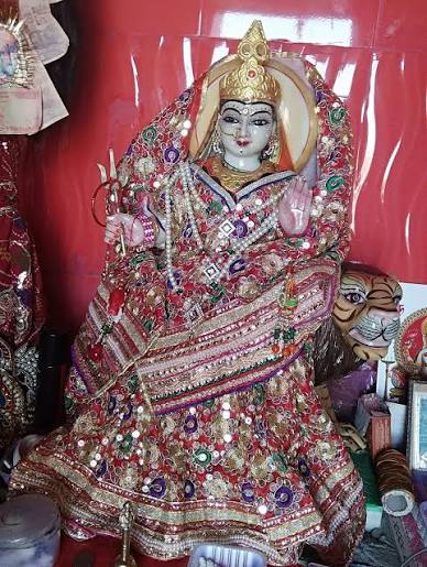 Marble idol of Maa Durga in a gold crown and embroidered red chunari, seated with her lion, representing the Durga form of Jeen Mata